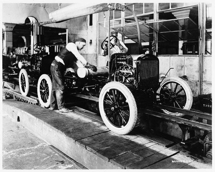 A worker assembling Ford Model T automobiles on a moving assembly line at the Highland Park plant in Detroit
